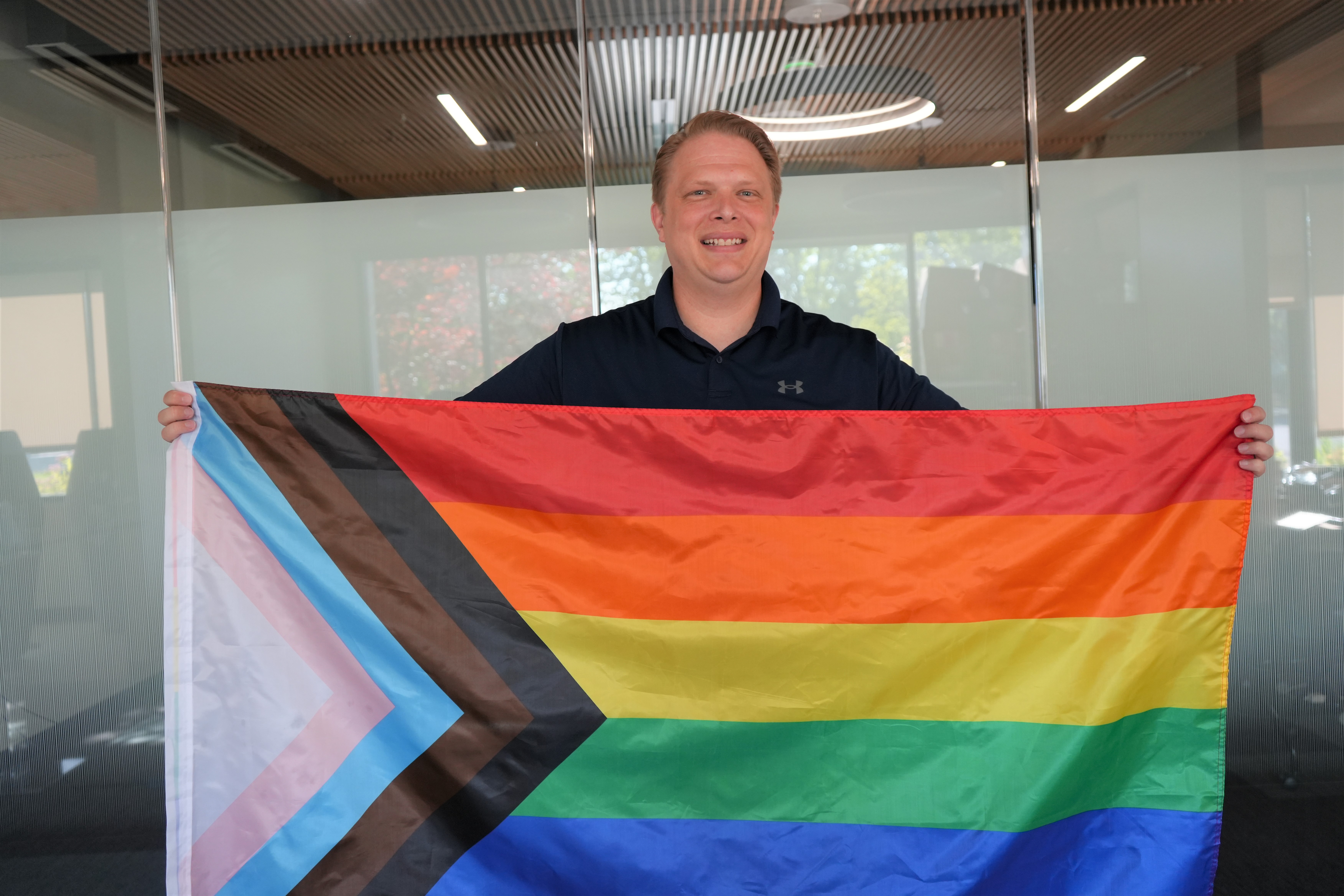 Dr. Allred holding the progressive Pride flag at HealthPoint