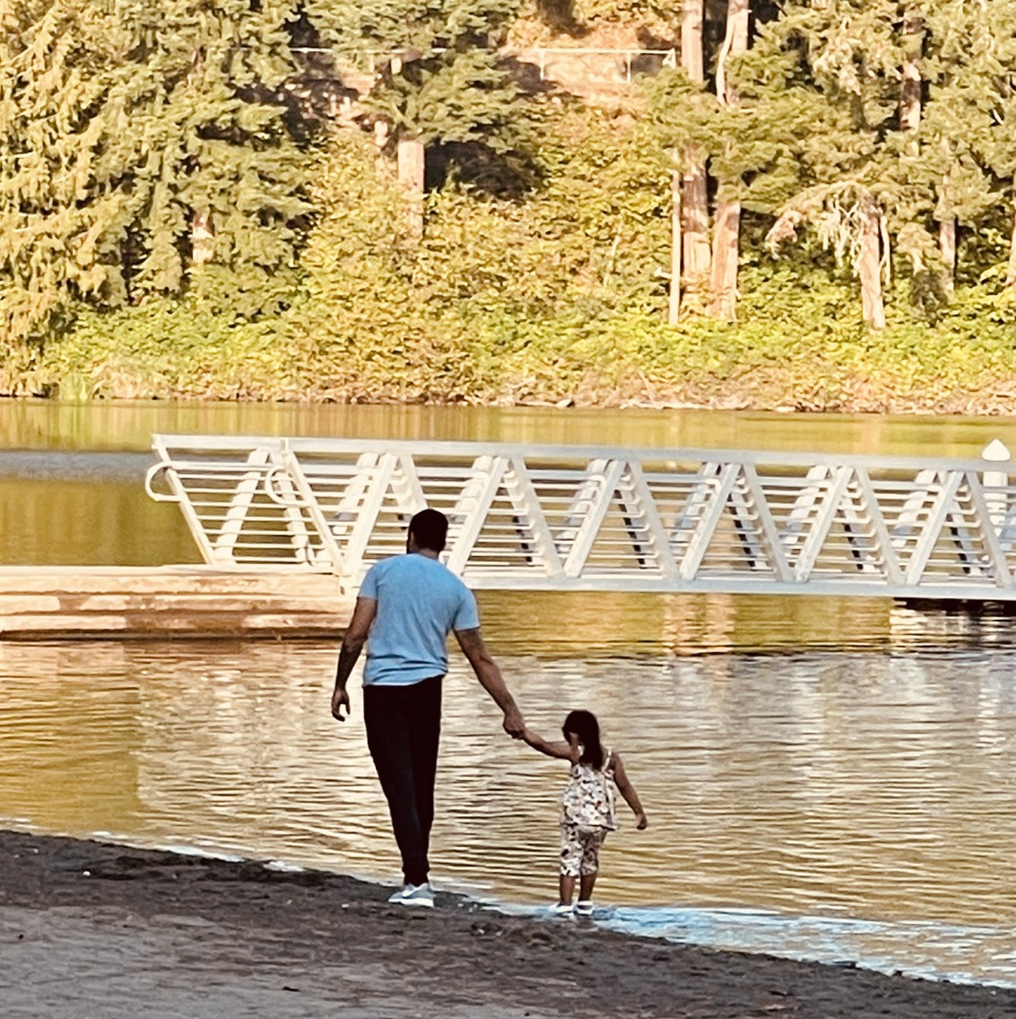 Sundeep walking with daughter alongside riverbank.